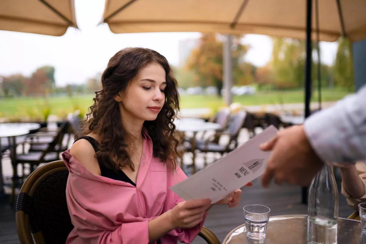 Cliente em restaurante analisando o cardápio, ilustrando como a apresentação estratégica do menu influencia no aumento do ticket médio.