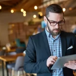 Gestor de restaurante utilizando um tablet para acompanhar dados, reforçando o papel da tecnologia na gestão e no crescimento do ticket médio.