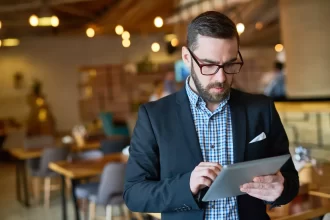 Gestor de restaurante utilizando um tablet para acompanhar dados, reforçando o papel da tecnologia na gestão e no crescimento do ticket médio.