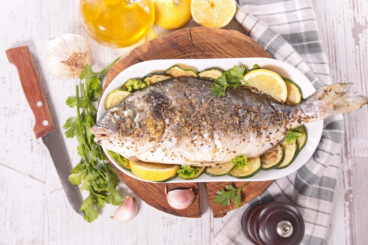 Peixe grelhado com abobrinha, limão e ervas, um prato leve e fresco, ideal como comida de primavera para restaurante.