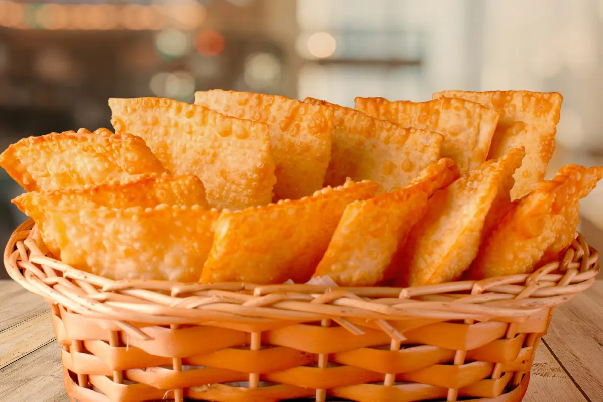 Uma cesta de vime repleta de pequenos pastéis fritos e dourados, dispostos de forma apetitosa em um ambiente com foco em negócio de pastelaria.