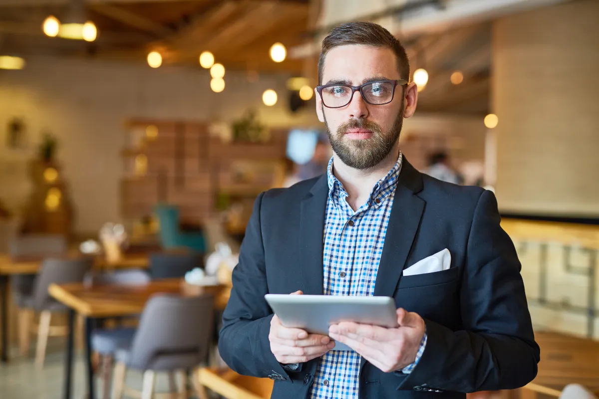 Gerente de restaurante com tablet em mãos avaliando dados de vendas, simbolizando a gestão moderna orientada por tecnologia para potencializar os resultados do negócio