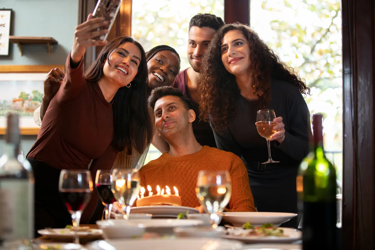 Grupo de amigos tirando selfie em restaurante, ilustrando o engajamento e a fidelização conquistados através de estratégias eficientes de marketing local para restaurantes
