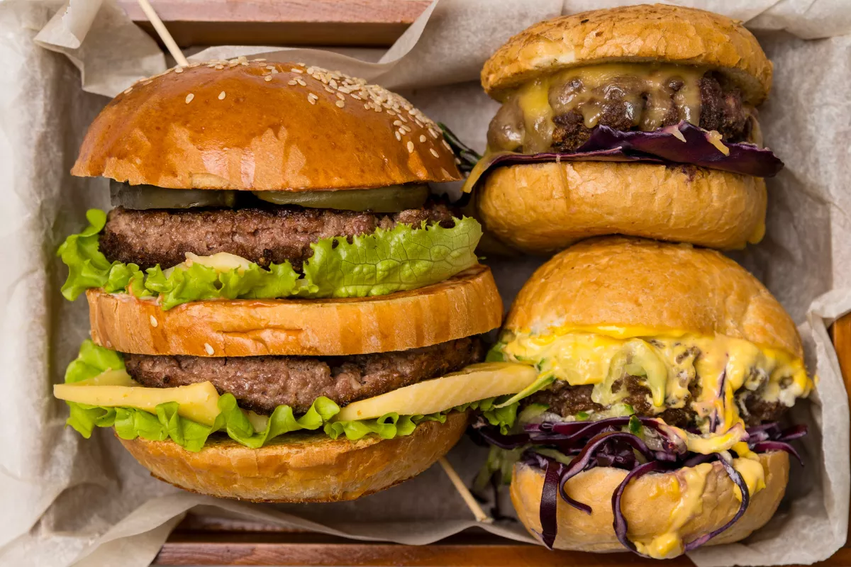 Caixa de madeira contendo quatro hambúrgueres artesanais de sabores variados, ideal para delivery e grupos, representando a ideia de Combo Box Experience para hamburguerias.