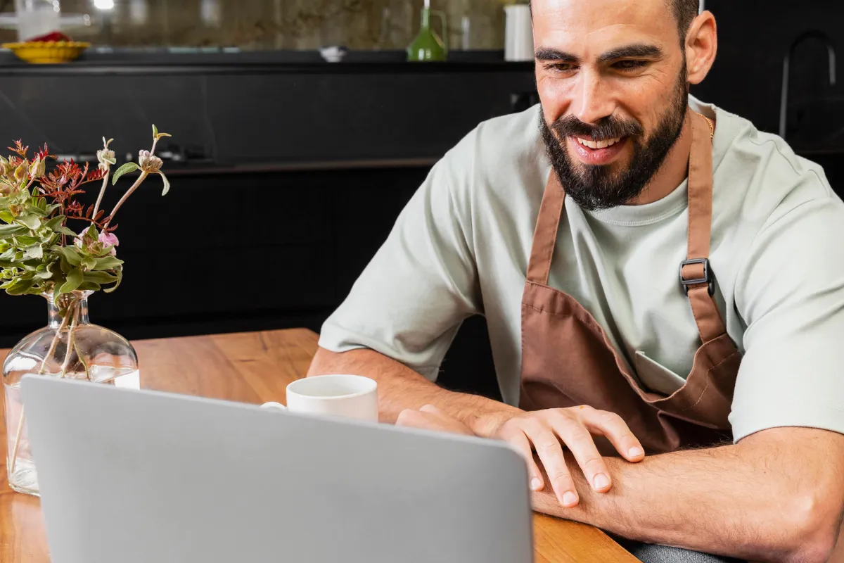 Dono de restaurante sorrindo enquanto analisa dados financeiros e de estoque em um laptop. A imagem representa a gestão eficiente do negócio e o uso de tecnologia para controlar os custos do churrasco