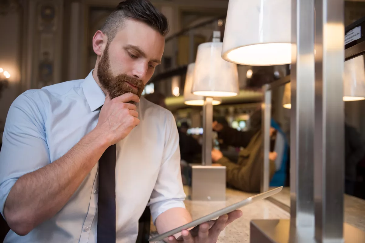 Gerente de food service analisando atentamente informações em um tablet, ilustrando o conceito de análise preditiva e o cruzamento de histórico de vendas para tomada de decisão estratégica.