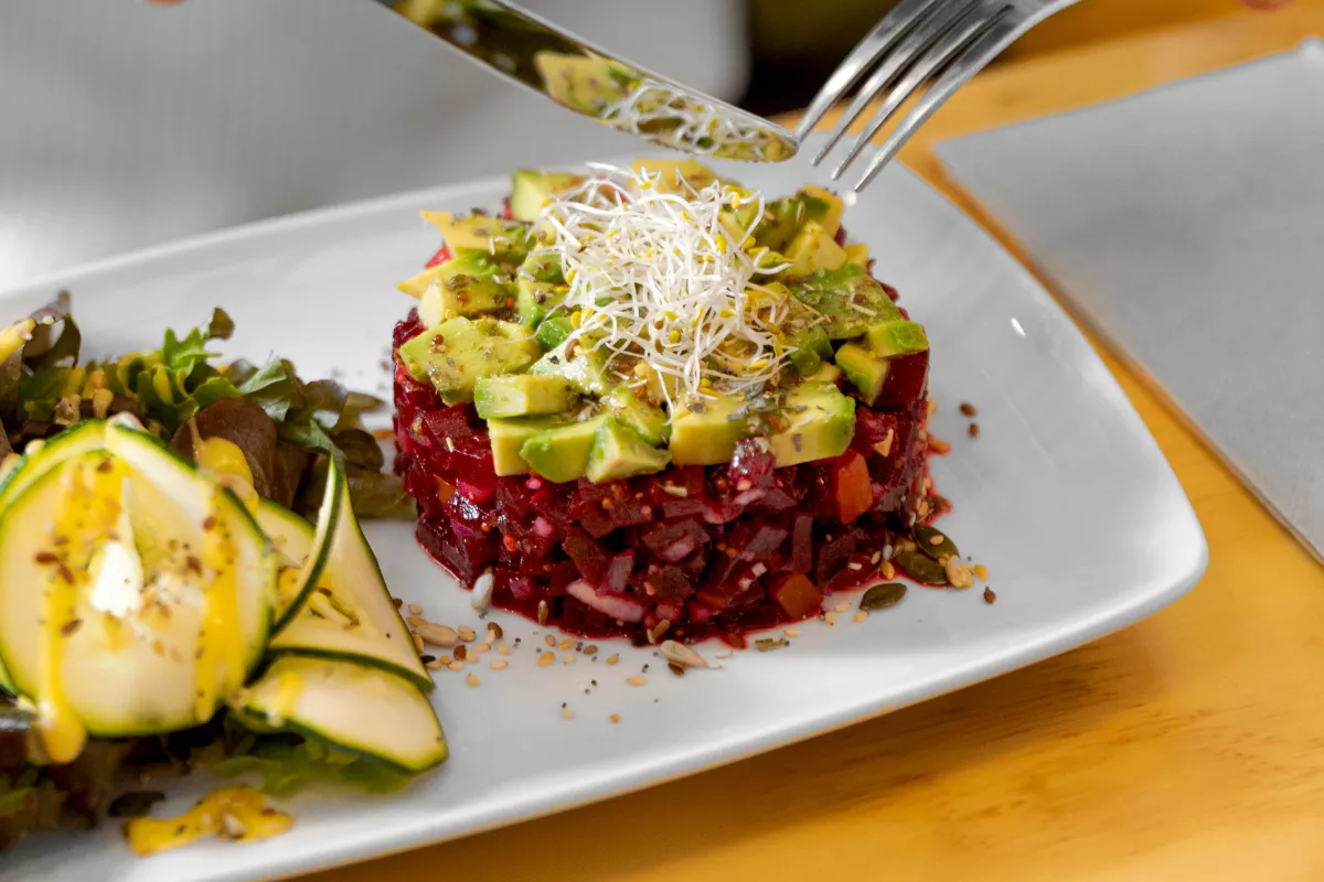 Prato de tartar de beterraba com abacate fatiado e brotos, servido em restaurante plant-based — exemplo de cardápio para restaurante de nicho saudável
