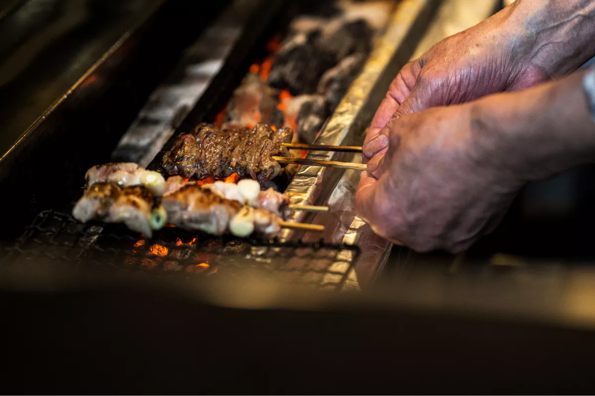 Espetinhos de carne sendo grelhados na brasa, representando a diversidade de preparos e variações de um mesmo ingrediente no cardápio do restaurante
