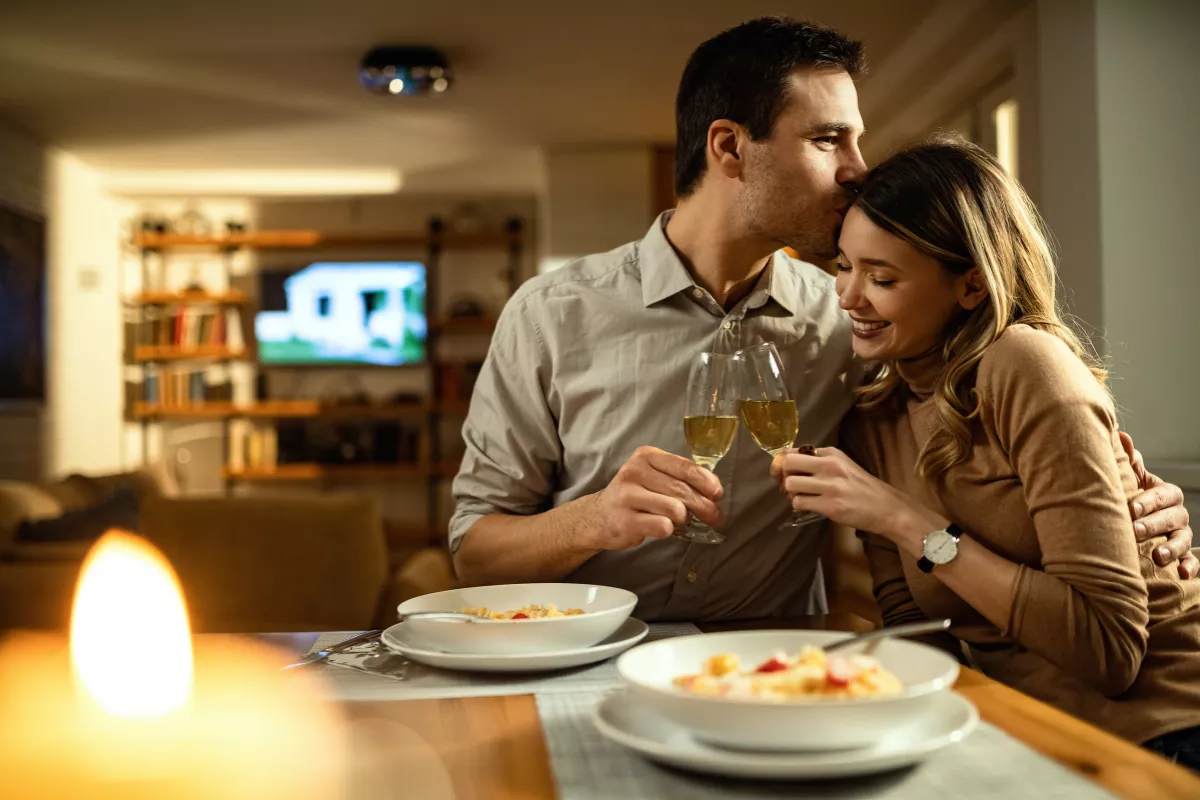 Casal jantando em clima romântico com taças de vinho, ilustrando como menus temáticos e datas comemorativas criam experiências especiais no restaurante