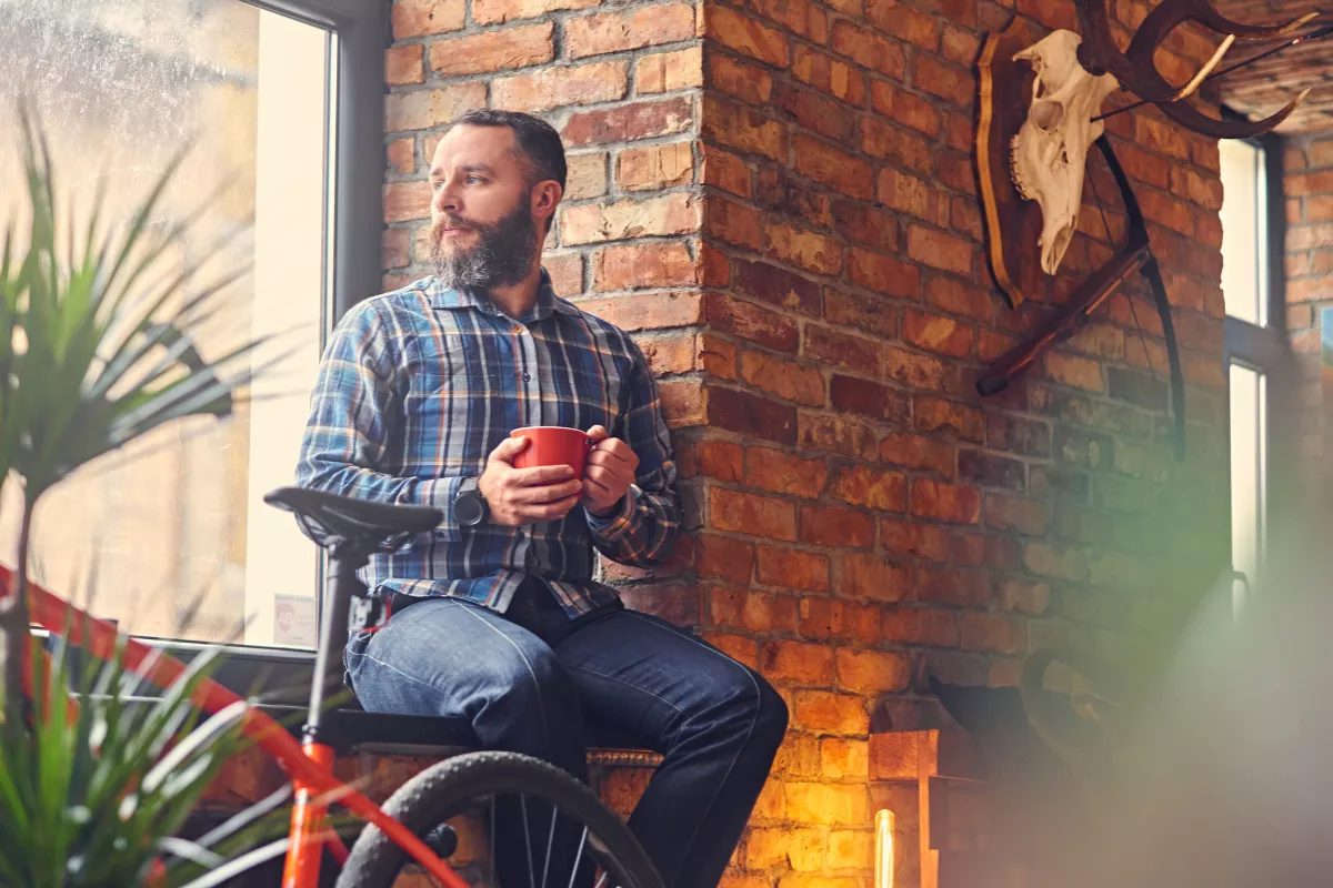 Homem com bicicleta ao lado tomando café em ambiente rústico com parede de tijolos — café de nicho para ciclistas, conceito de restaurante de nicho
