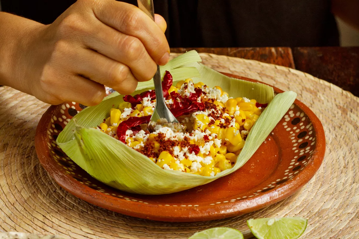 Prato típico regional com milho, queijo e pimenta servido em louça de barro, ilustrando o uso de ingredientes sazonais e locais para variar o cardápio do restaurante