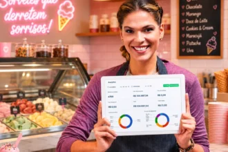 Dona de sorveteria de avental sorrindo segurando tablet com dashboard de analytics, com balcão refrigerado de sorvetes coloridos e cardápio em lousa ao fundo